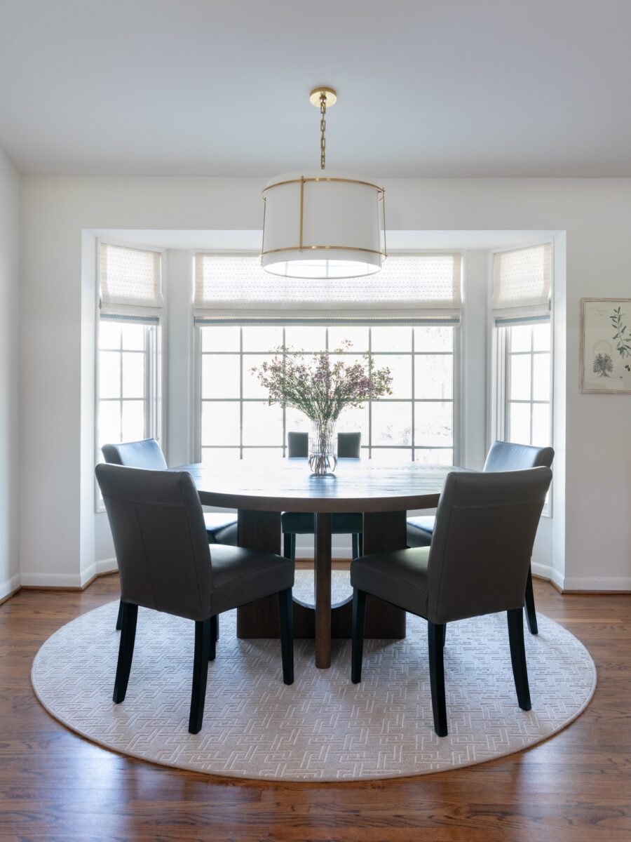 Photo of dining area after redesign. Features round dining table and round linen ceiling lamp.